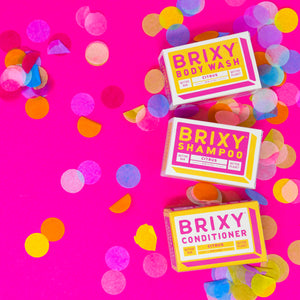 Pink confetti next to BRIXY Citrus shampoo and conditioner bar for oily hair. Shampoo and conditioner bar for fine hair. Shampoo and conditioner bar for curly hair. Shampoo and conditioner bar for thinning hair. Shampoo and conditioner bar for thick hair. Shampoo and conditioner bar for dry hair.